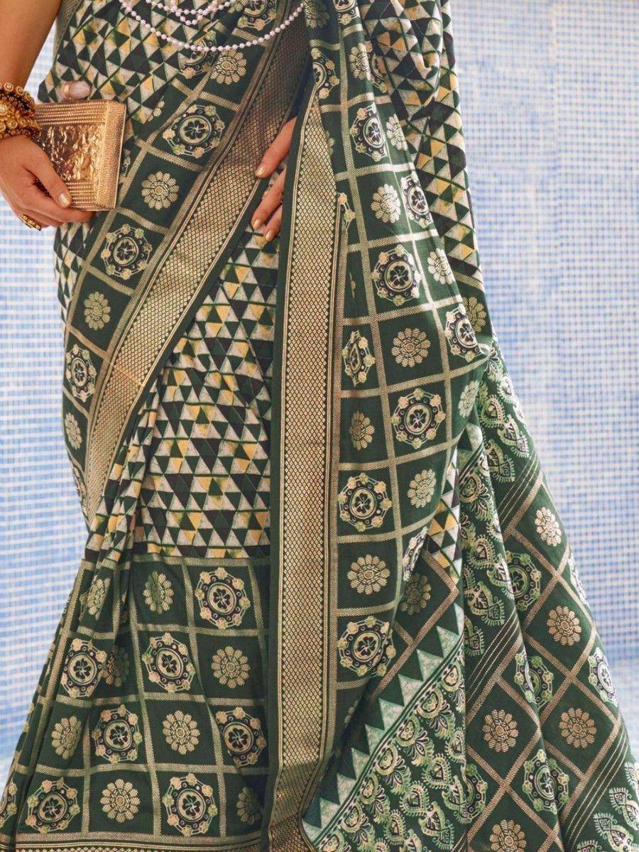 Green printed saree with geometric and floral motifs, gold border, paired with clutch and pearls