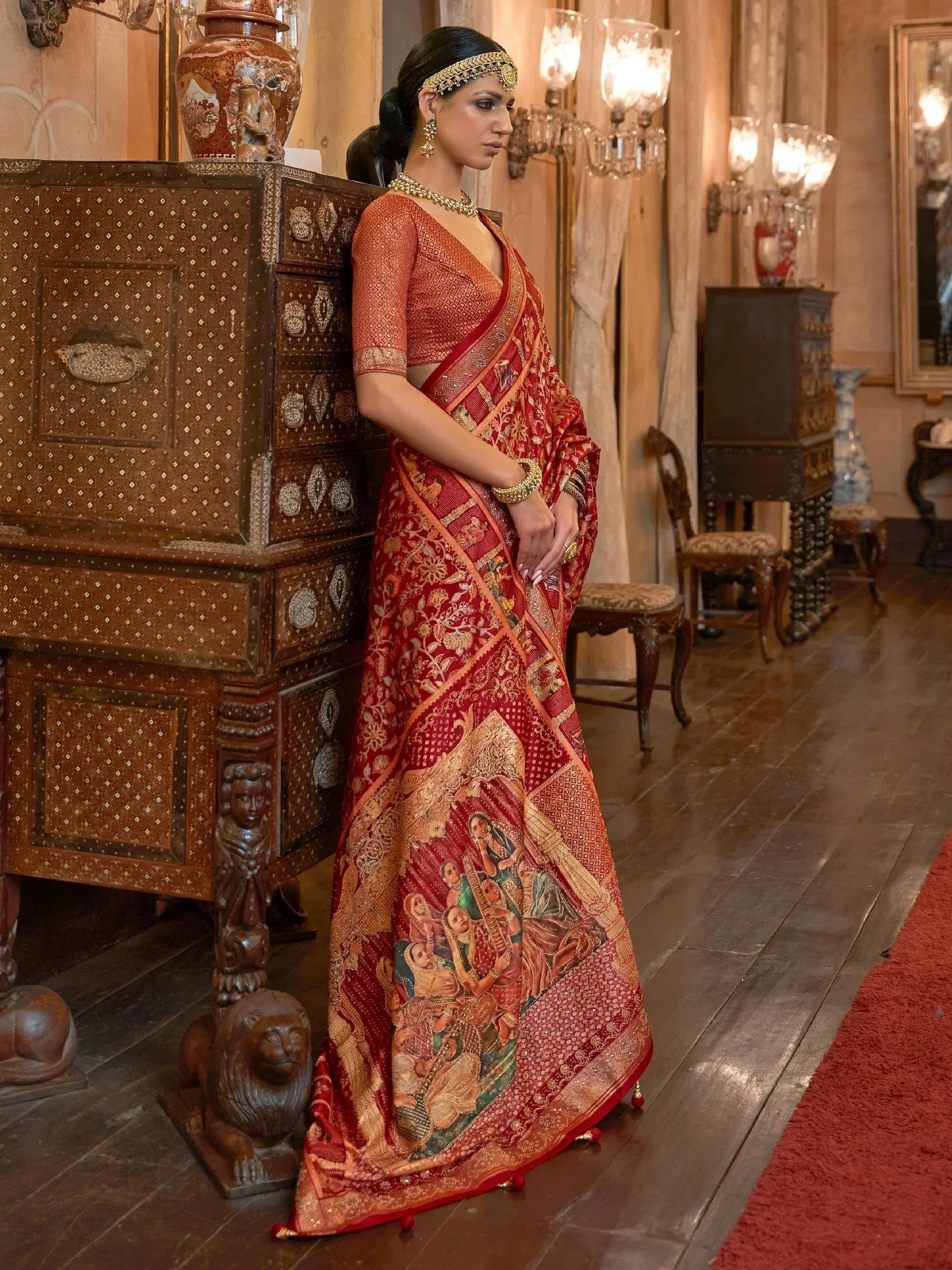 Woman in red and gold designer saree with intricate embroidery and traditional jewelry, styled for ethnic occasions