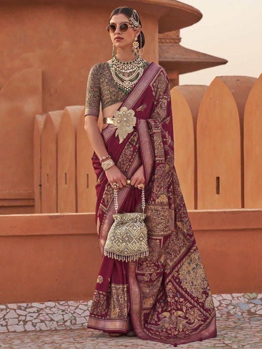 Elegant maroon designer saree with gold embroidery, paired with statement jewelry and a matching potli bag.