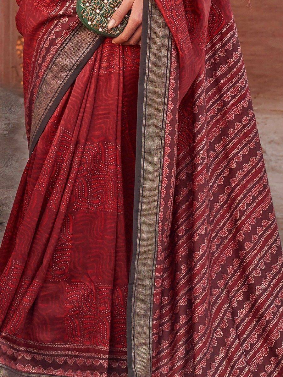 Red printed saree with gold border and ethnic motifs, styled with green clutch for traditional Indian wear