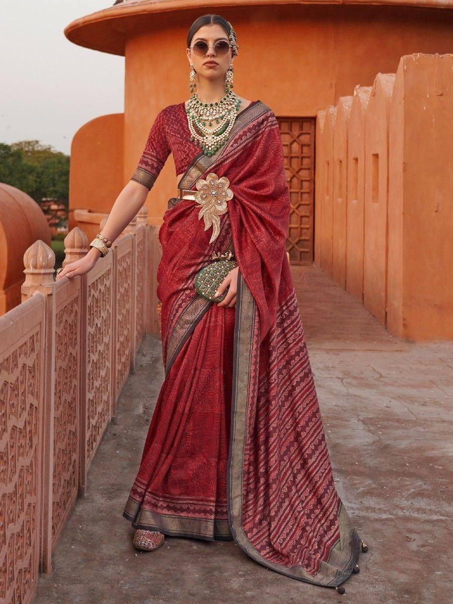 Elegant maroon ethnic saree with gold embroidery, paired with traditional jewelry and sunglasses, perfect for festive occasions.