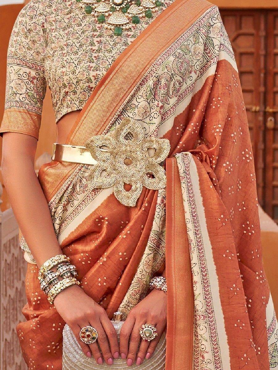 Elegant orange and cream saree with floral blouse, embellished belt, and traditional jewelry for Indian ethnic wear