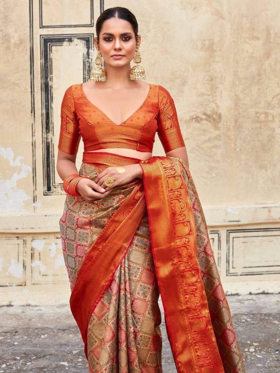 Orange designer saree with intricate gold and green patterns, paired with matching blouse and traditional jewelry