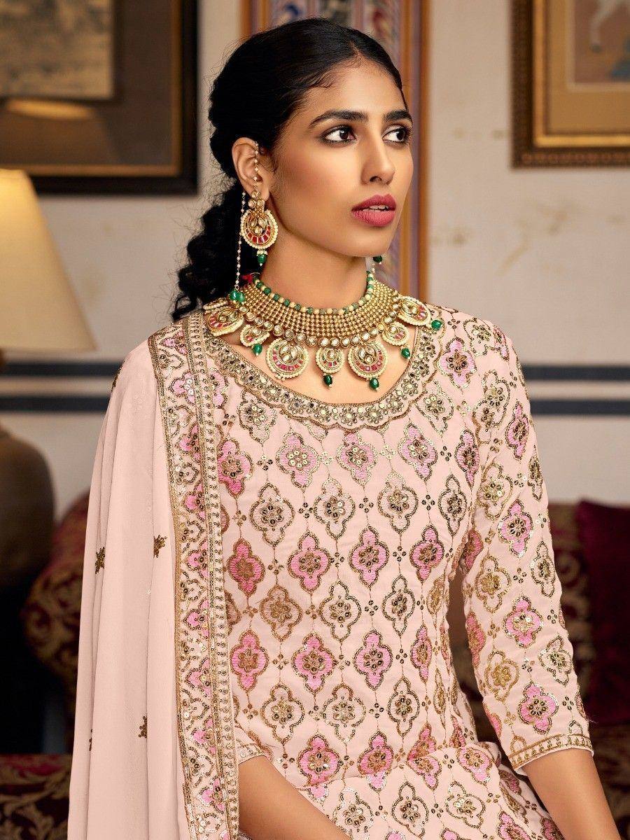 Pink embroidered salwar kameez with gold detailing and traditional Indian jewelry