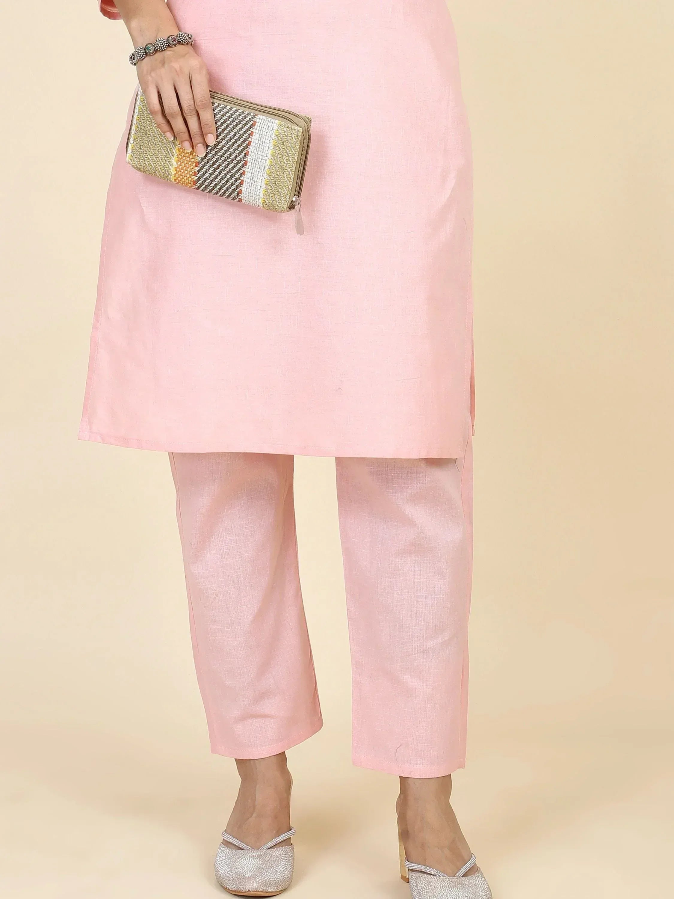 Pink ethnic kurta with matching pants, styled with woven clutch and silver heels for Indian wear