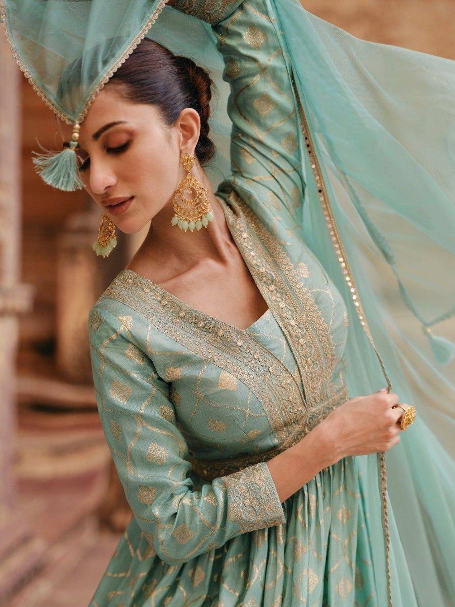 Mint green ethnic gown with gold embroidery, matching dupatta, and traditional jewelry for Indian occasions