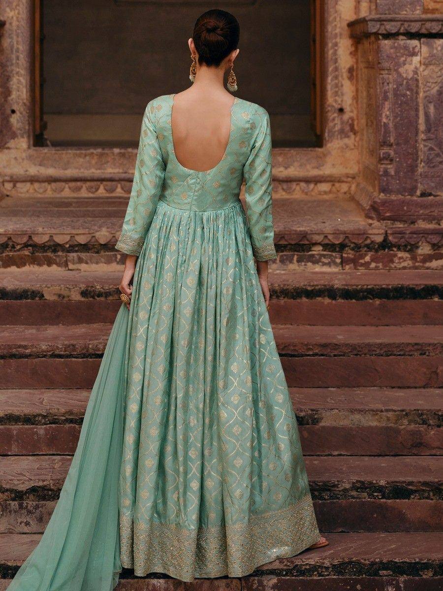 Mint green ethnic gown with gold embroidery, backless design, standing on stone steps