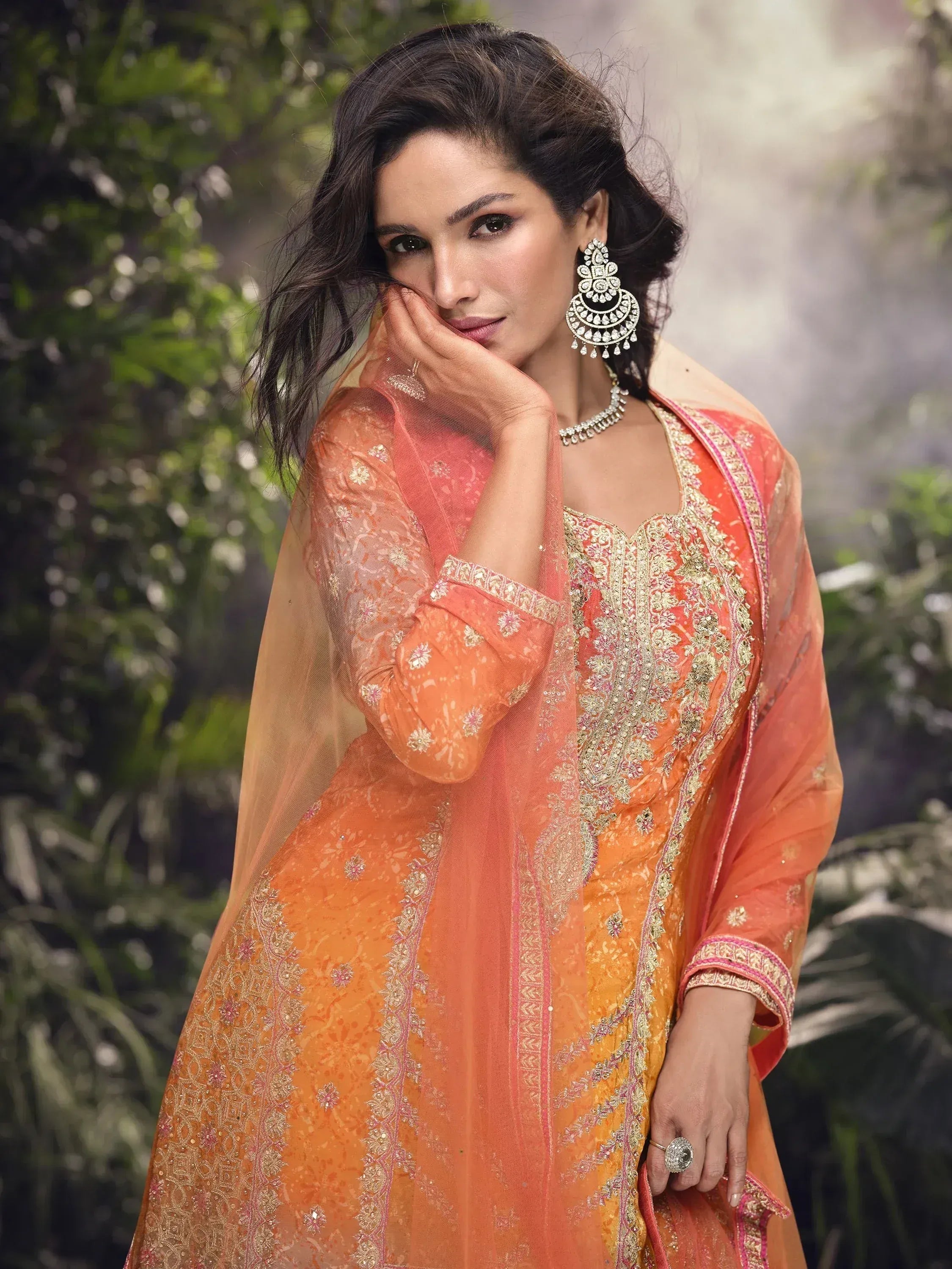Orange embroidered Indian salwar kameez with gold detailing and matching dupatta, styled with jhumka earrings.