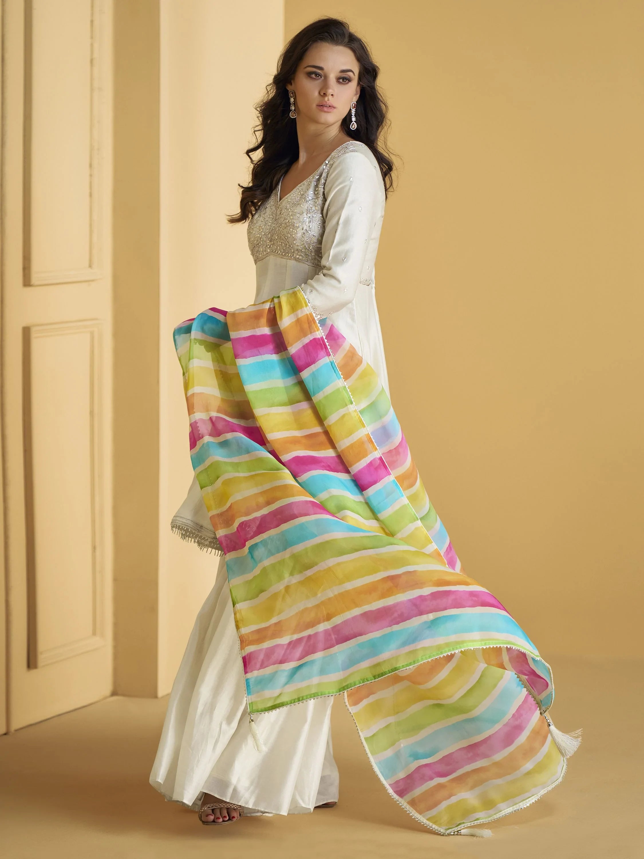 Woman wearing ivory ethnic gown with sequin bodice and multicolor striped dupatta