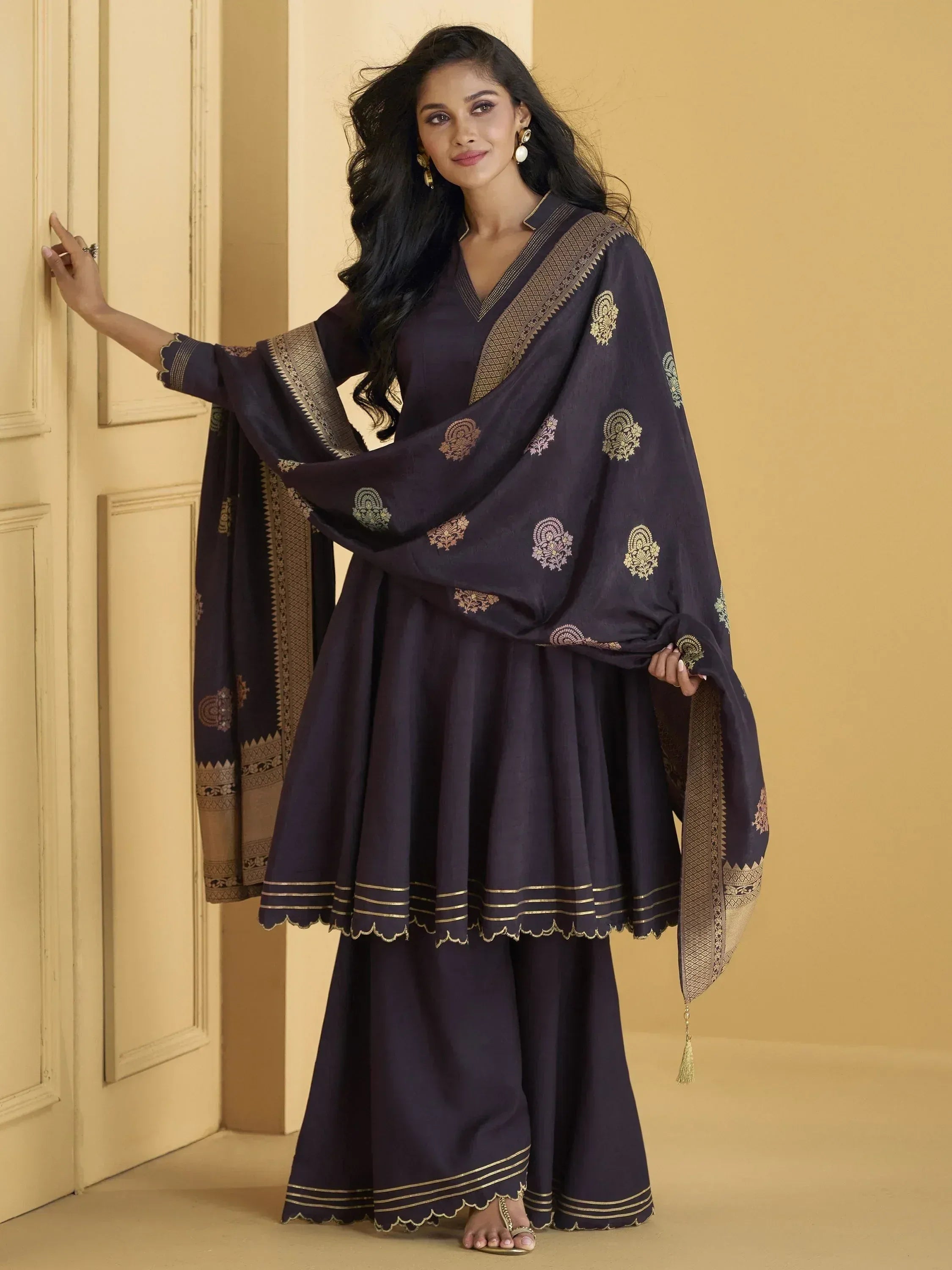 Dark purple ethnic salwar kameez with gold embroidery and scalloped hem, paired with matching dupatta