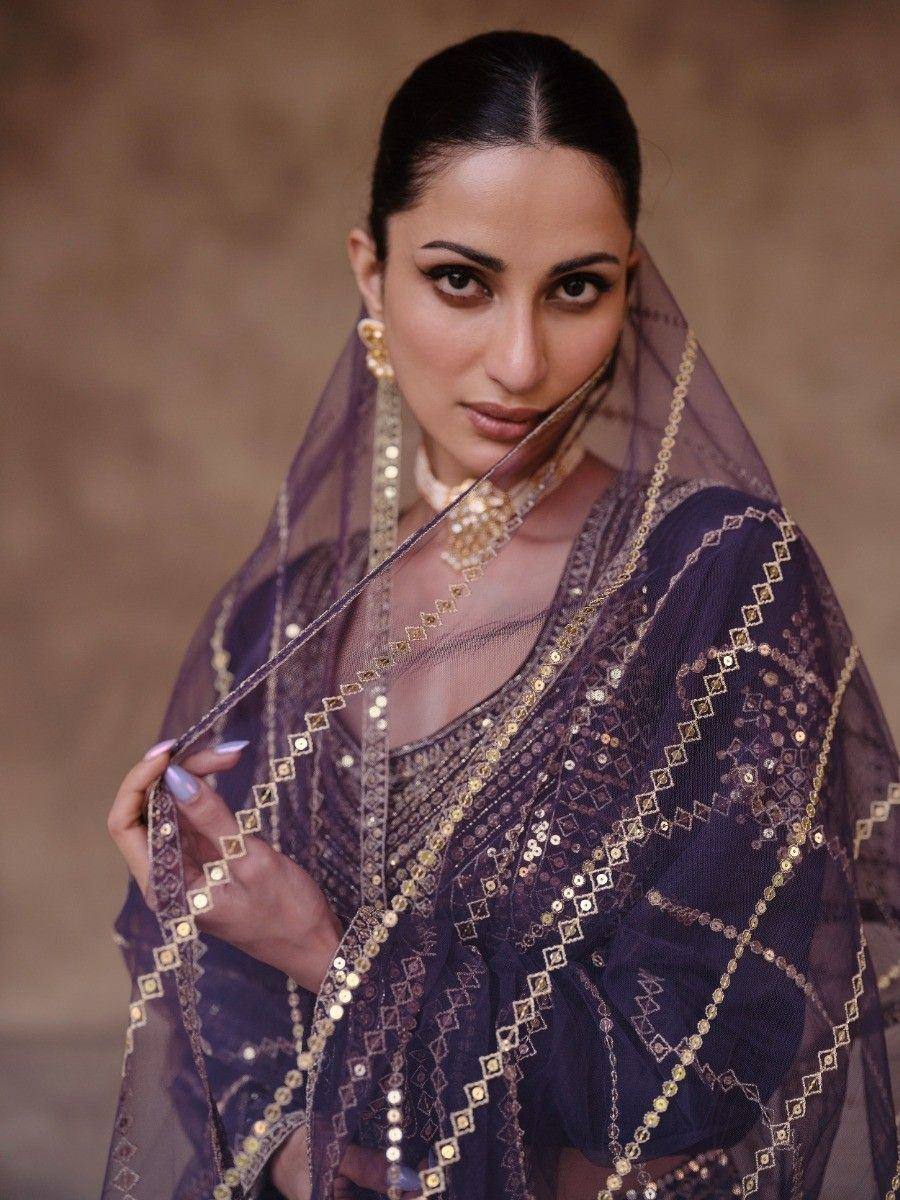 Elegant purple ethnic saree with gold mirror work and sheer dupatta, perfect for Indian weddings and festive occasions.