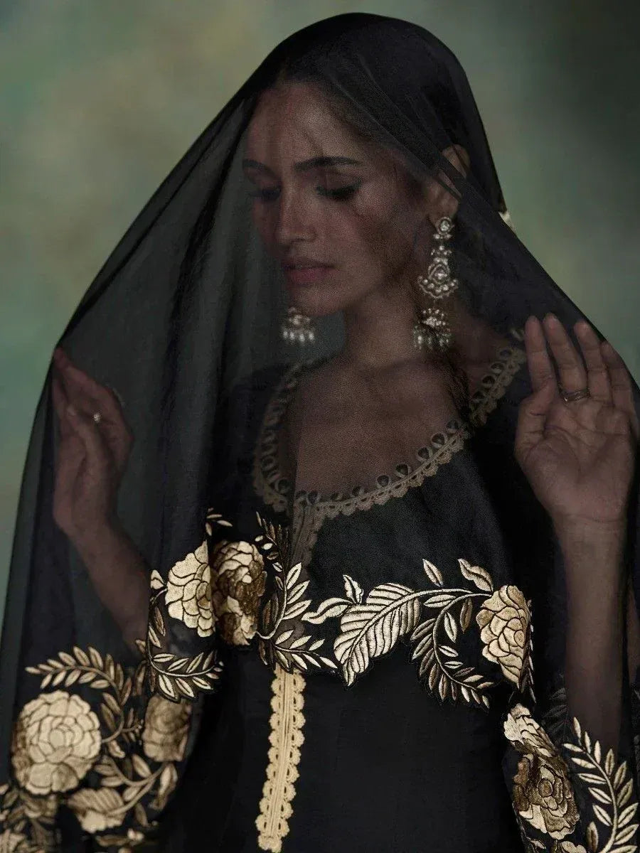 Black ethnic gown with gold floral embroidery and sheer dupatta, styled with traditional jewelry