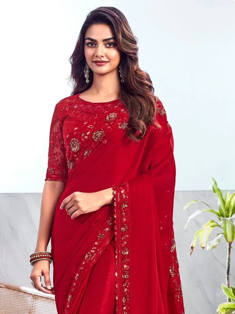 Red embroidered saree with gold detailing, styled with matching blouse and jewelry for ethnic occasions