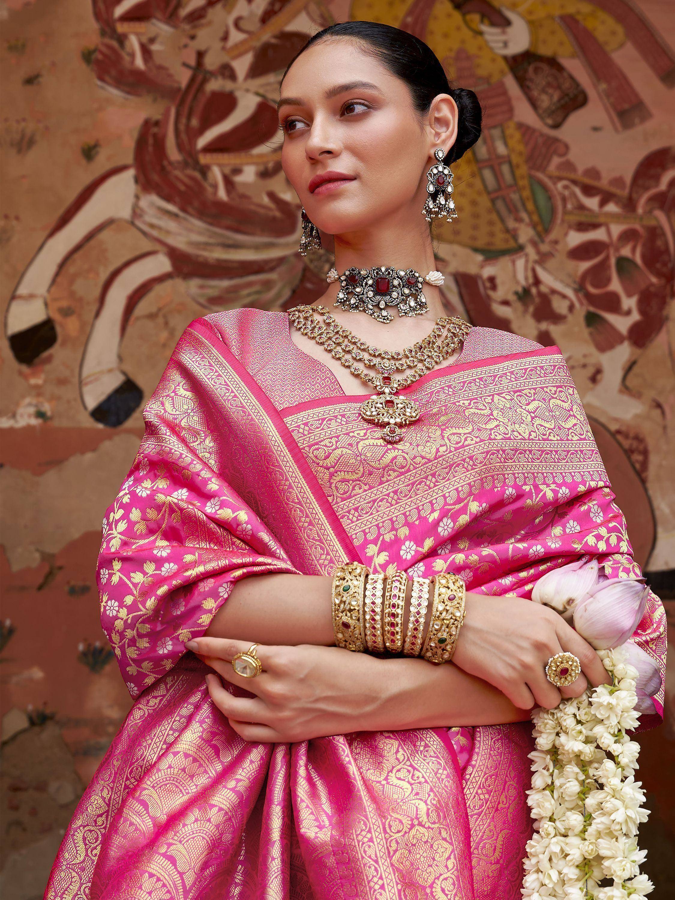 Pink and gold embroidered ethnic saree with traditional jewelry and floral garland