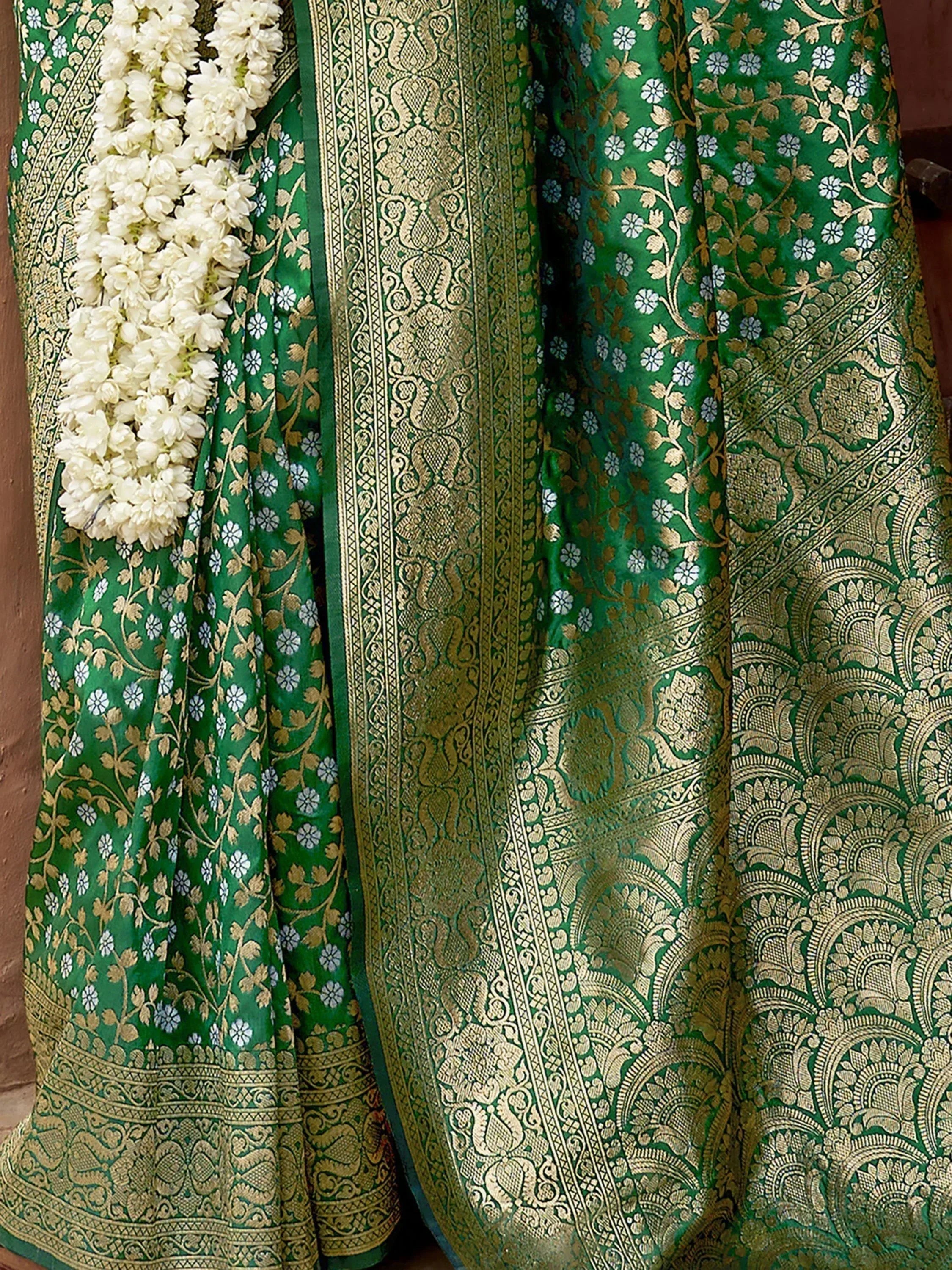 Green and gold floral Banarasi saree with intricate zari work and white jasmine garland