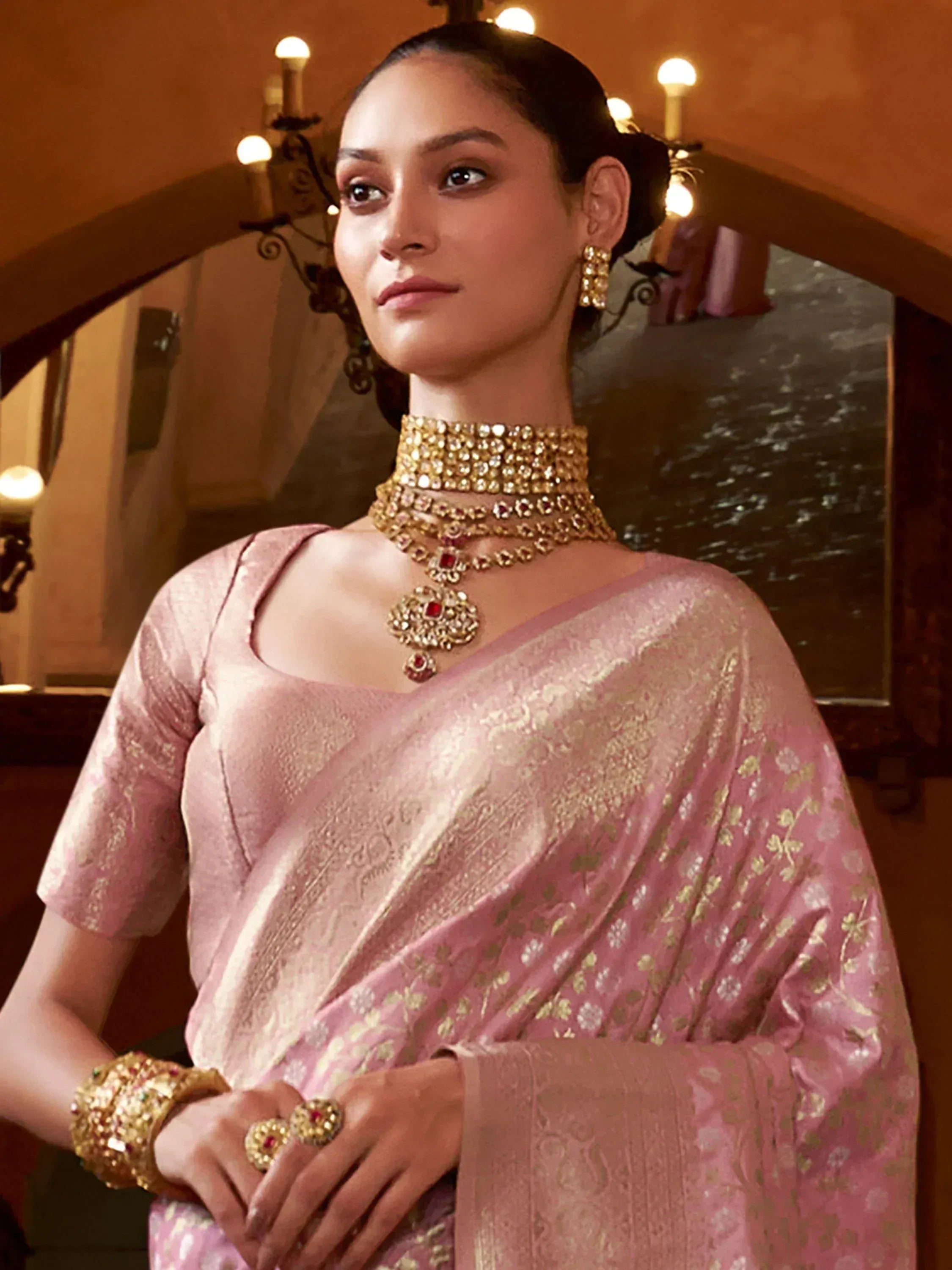 Elegant woman in pink floral saree with gold embroidery, paired with traditional Indian jewelry for festive occasions
