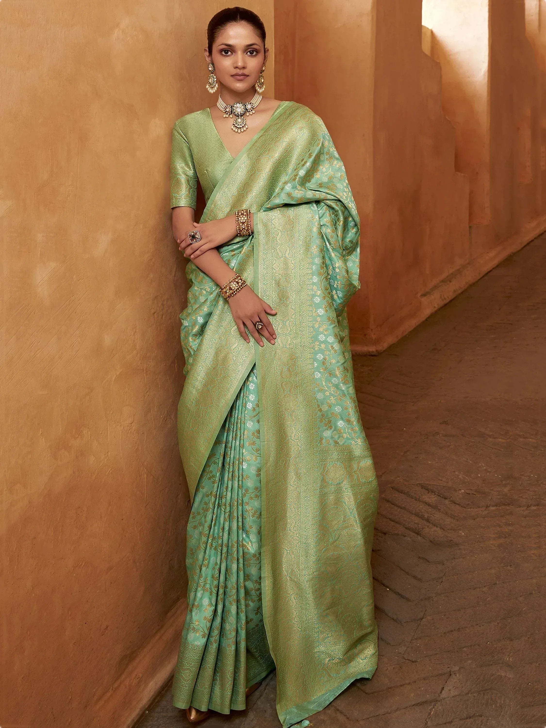 Mint green designer saree with gold floral embroidery, paired with matching blouse and traditional jewelry