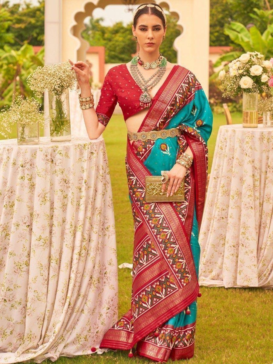 Woman in red and teal designer saree with intricate embroidery, perfect for Indian ethnic wear occasions