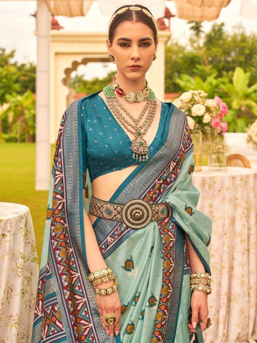 Teal designer saree with intricate border, paired with statement jewelry and waist belt for ethnic occasions