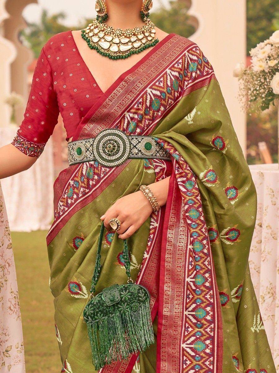 Green and red ethnic saree with intricate border, designer blouse, and statement jewelry for Indian occasions