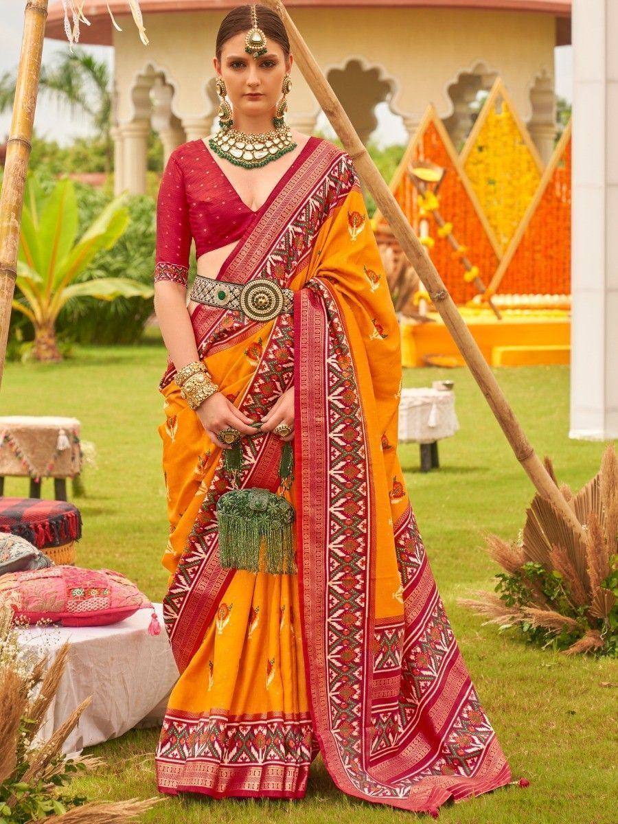 Vibrant orange and red ethnic saree with intricate patterns, paired with designer blouse and traditional jewelry for festive occasions