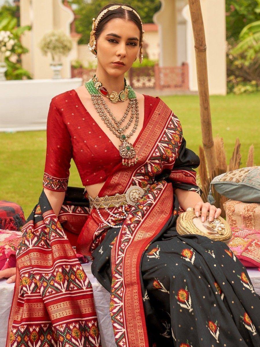 Elegant woman in red and black ethnic saree with intricate patterns and traditional jewelry