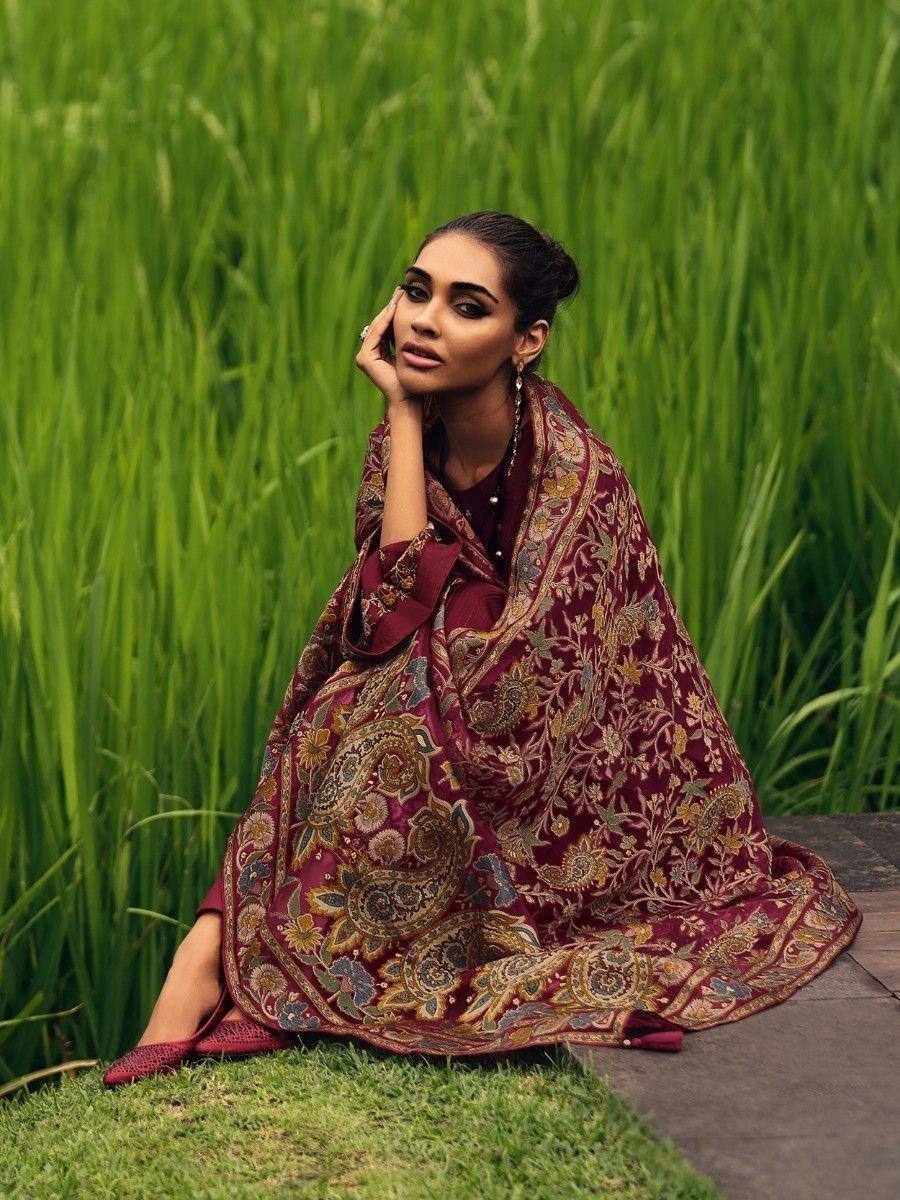 Elegant maroon ethnic gown with floral embroidery, styled in lush green field