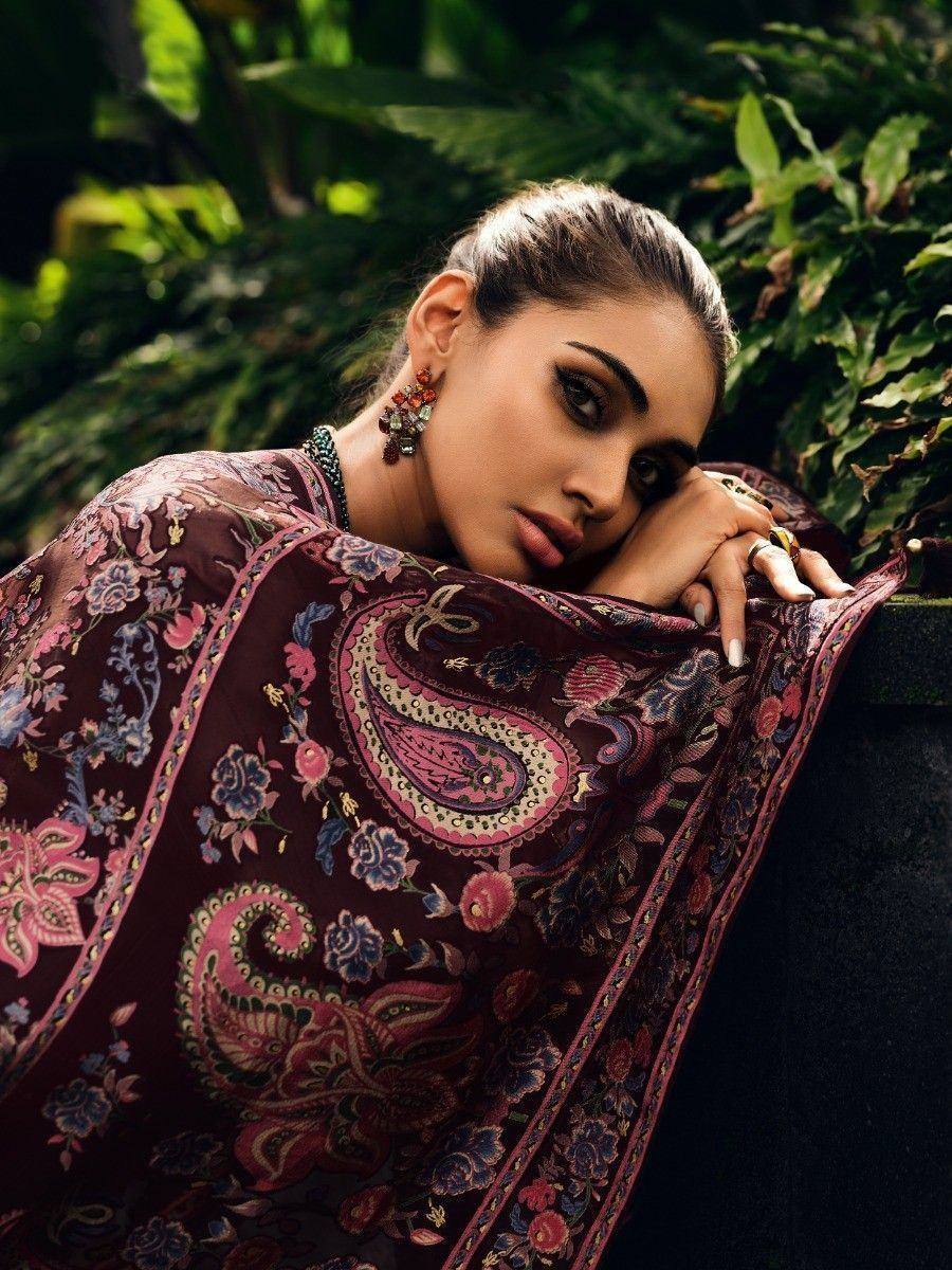 Woman in maroon floral paisley ethnic saree with statement jewelry, lush green backdrop