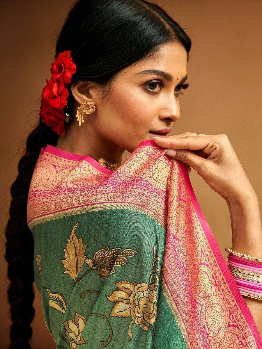 Green and pink designer saree with gold floral embroidery, styled with red hair flowers and traditional jewelry
