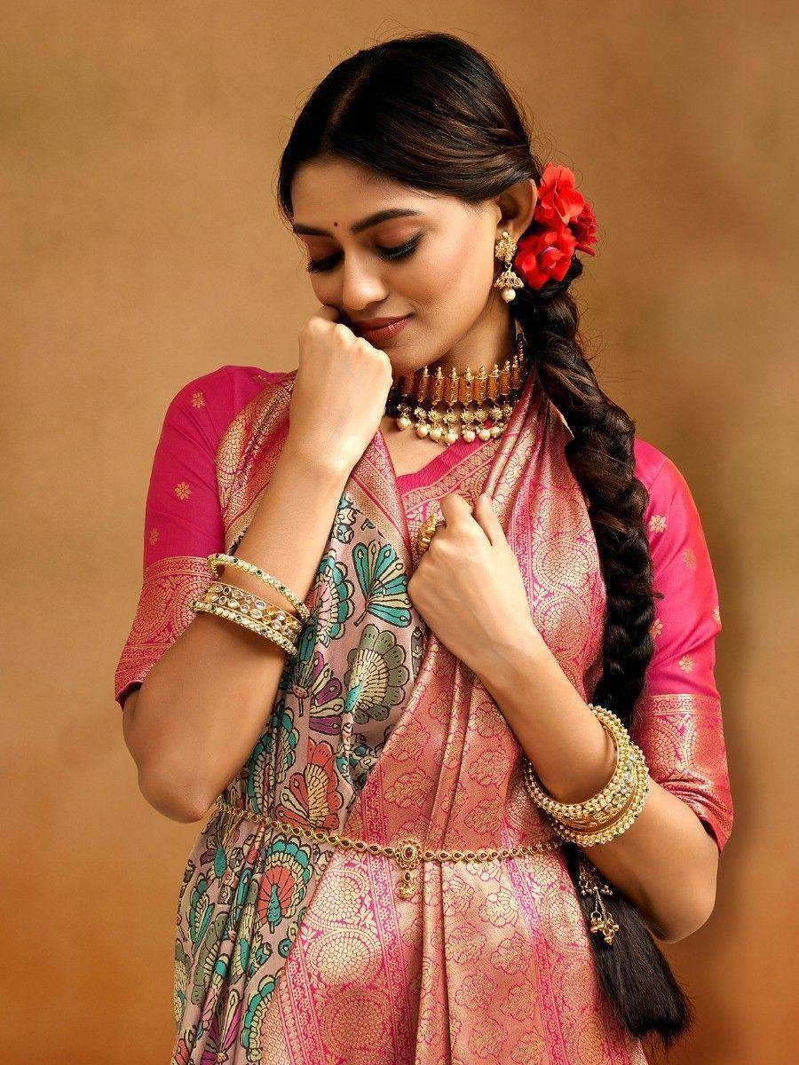 Woman in pink ethnic gown with floral dupatta, gold jewelry, and red hair flowers