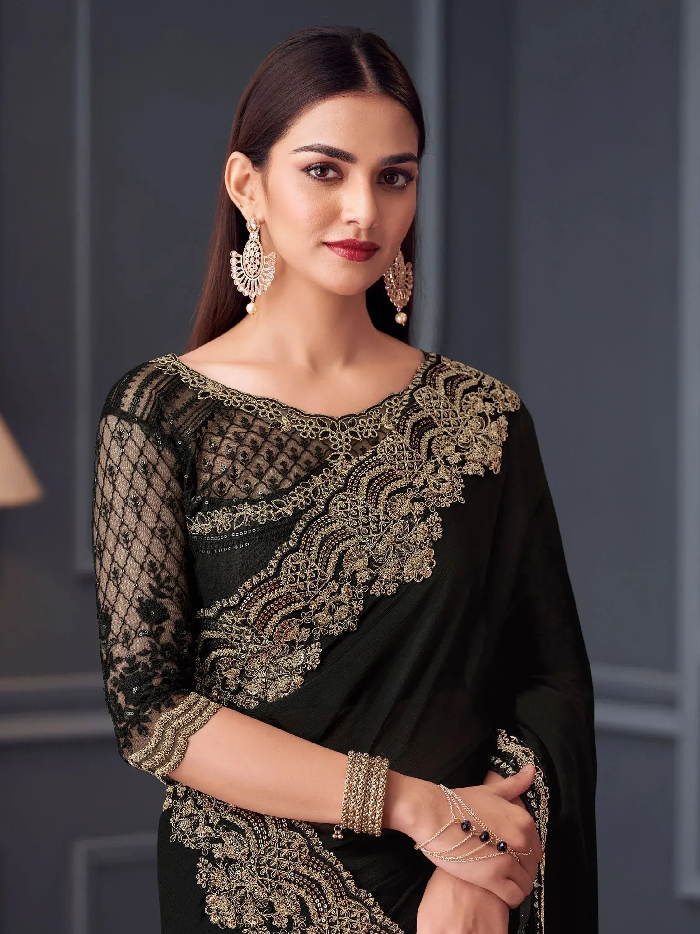 Elegant black saree with gold embroidery and sheer sleeves, paired with statement earrings for festive occasions.