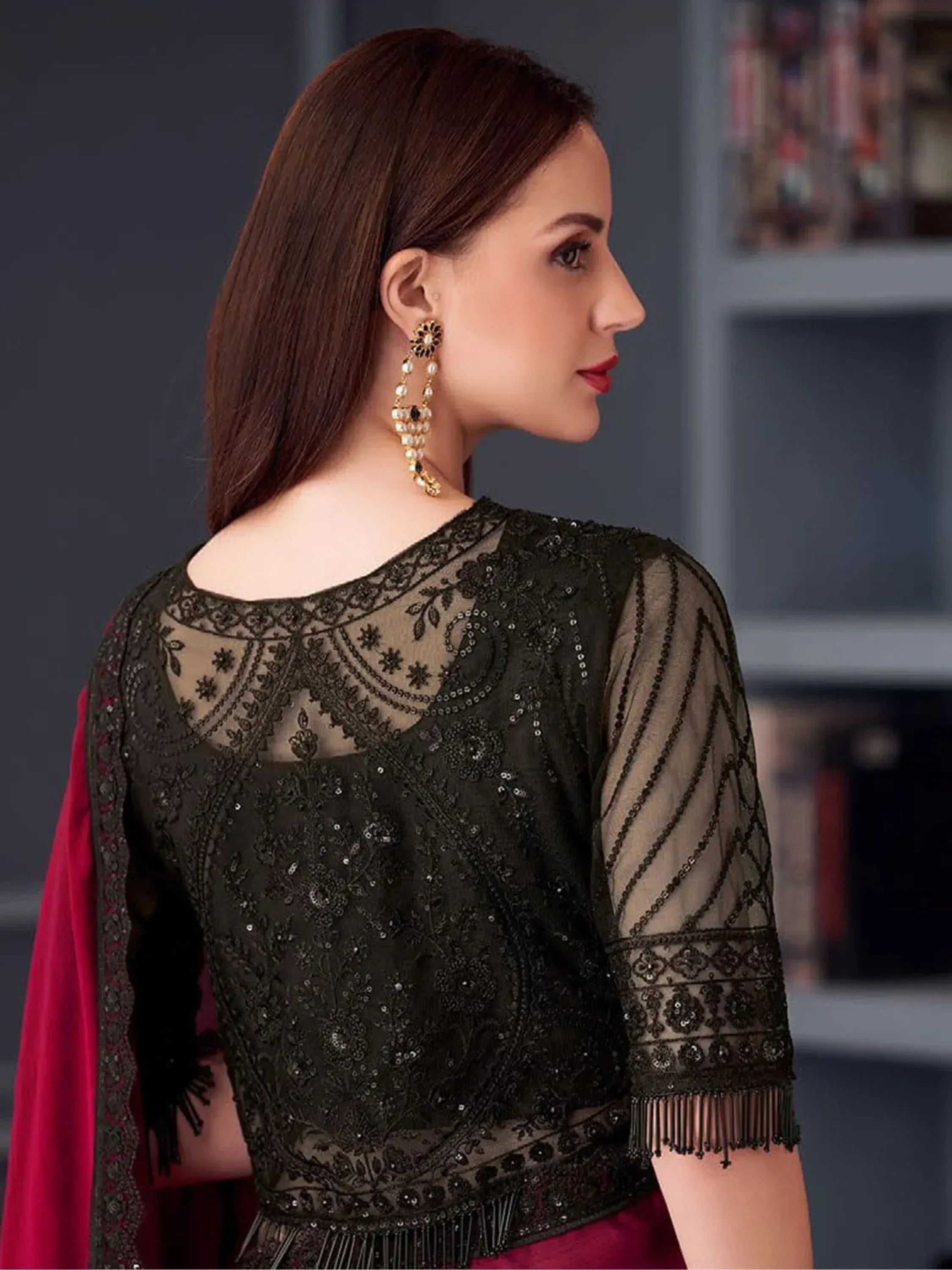 Black embroidered ethnic blouse with sheer sleeves and fringe, paired with red dupatta, showcasing designer Indian wear.