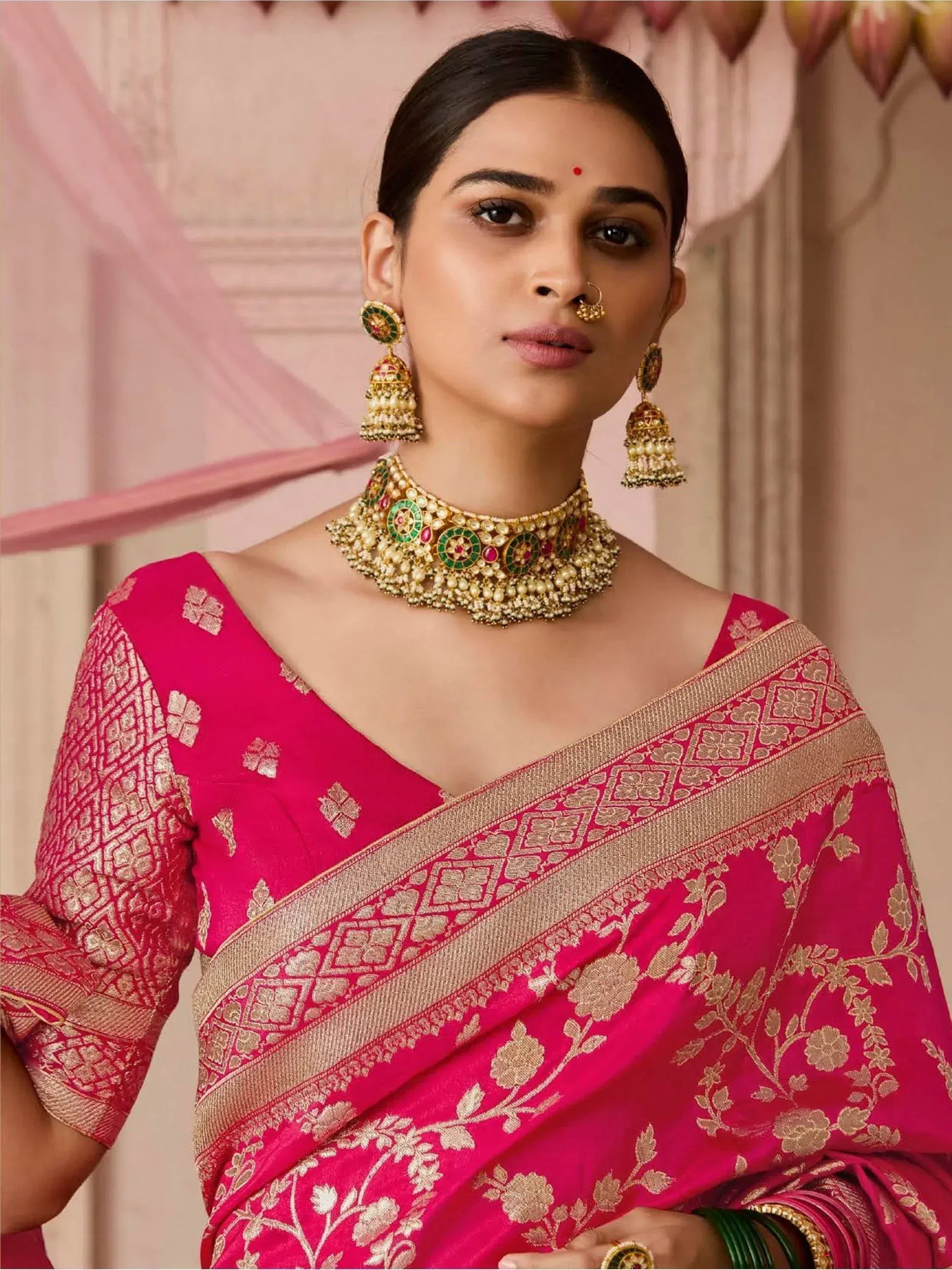 Woman in vibrant pink designer saree with gold embroidery, traditional jewelry, perfect for Indian ethnic wear occasions.