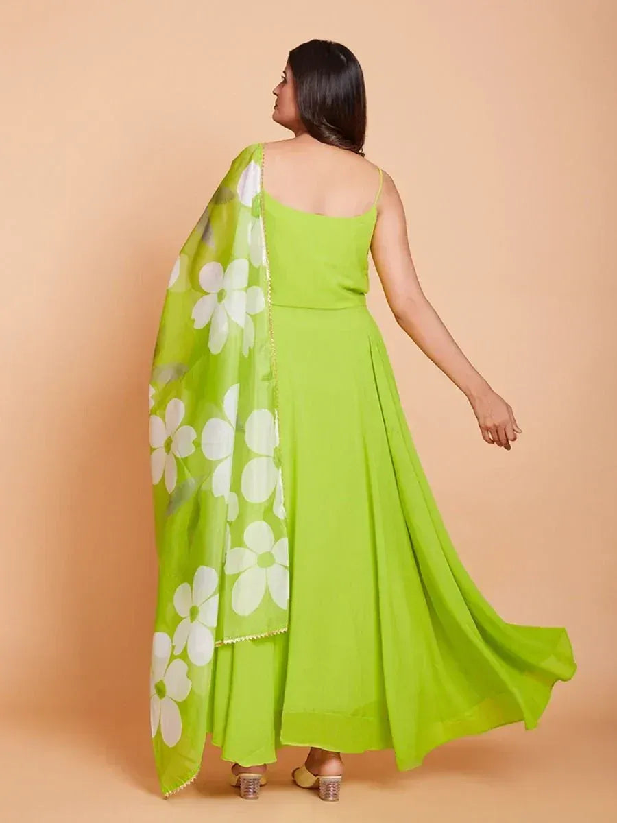 Woman in lime green lehenga choli with floral dupatta, back view on beige background