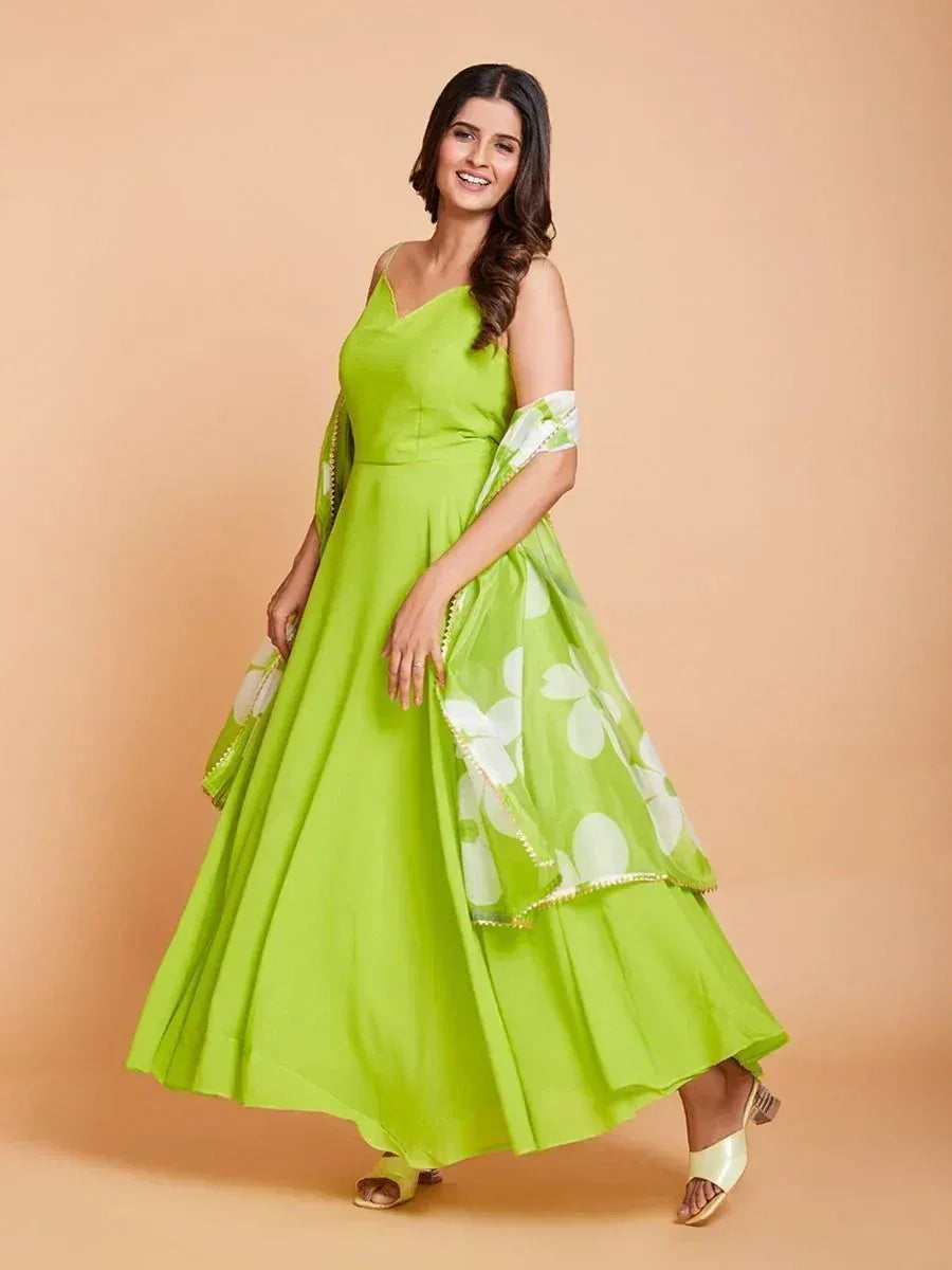 Woman wearing a lime green ethnic gown with floral dupatta and gold sandals