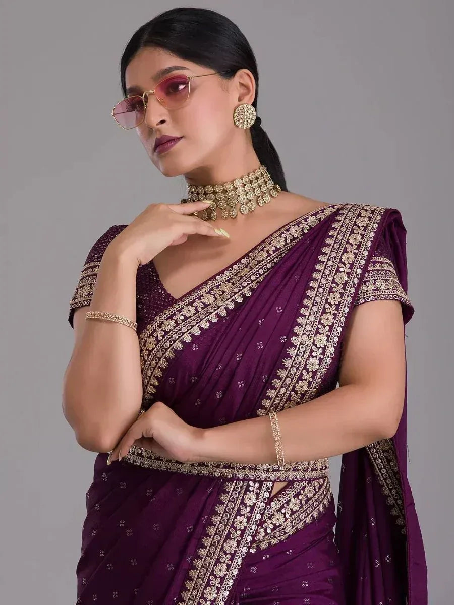 Elegant purple saree with gold embroidery, styled with statement jewelry and sunglasses for a modern ethnic look.