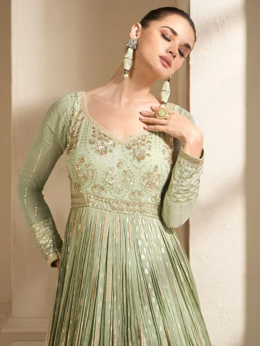 Mint green embroidered ethnic gown with gold detailing, perfect for Indian weddings and festive occasions.