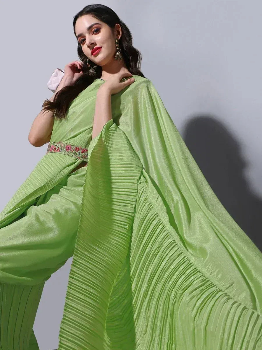 Lime green pleated saree with floral border, styled with statement earrings for ethnic wear