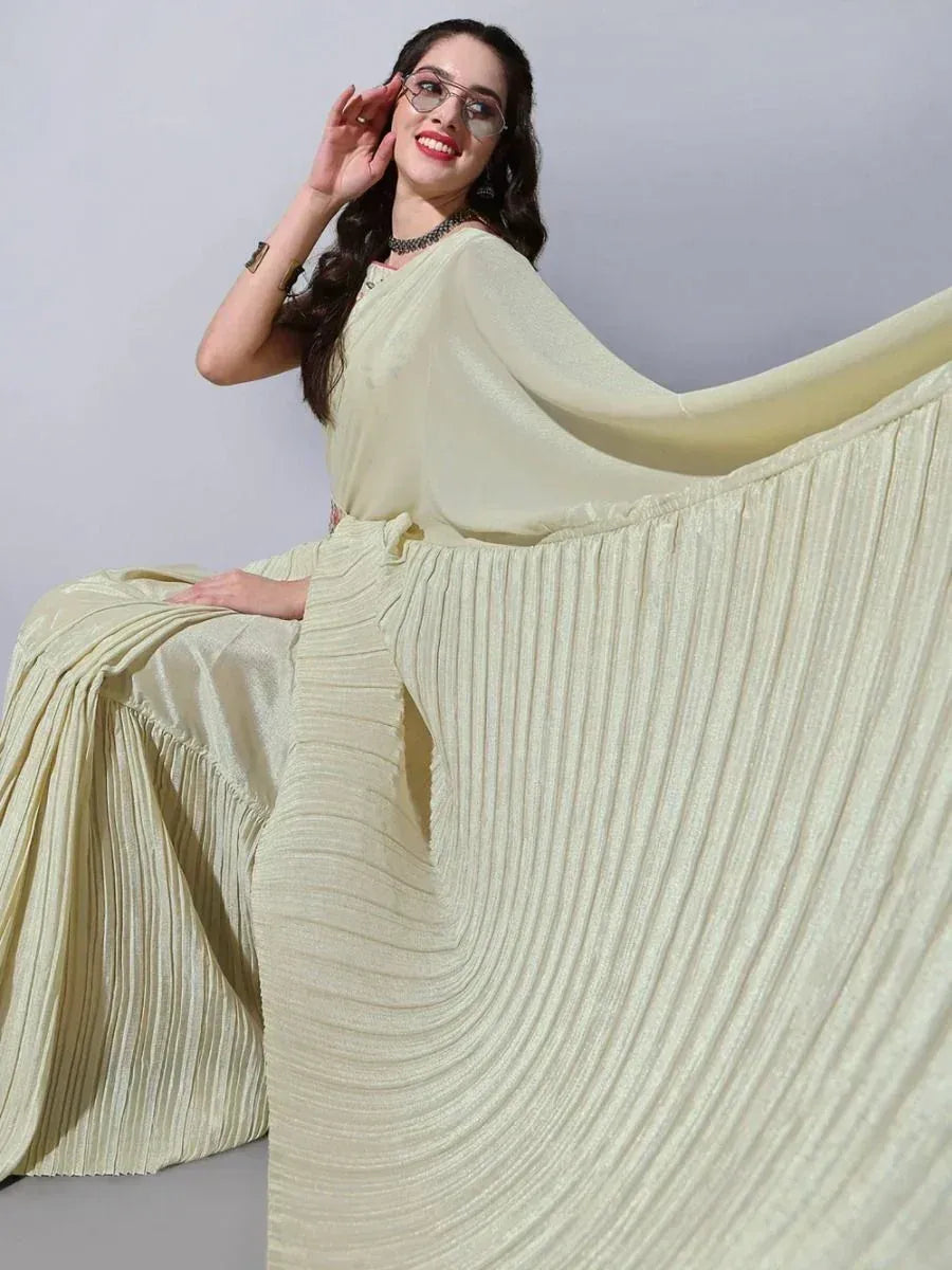Woman in elegant cream pleated ethnic gown with flowing cape, perfect for festive occasions.