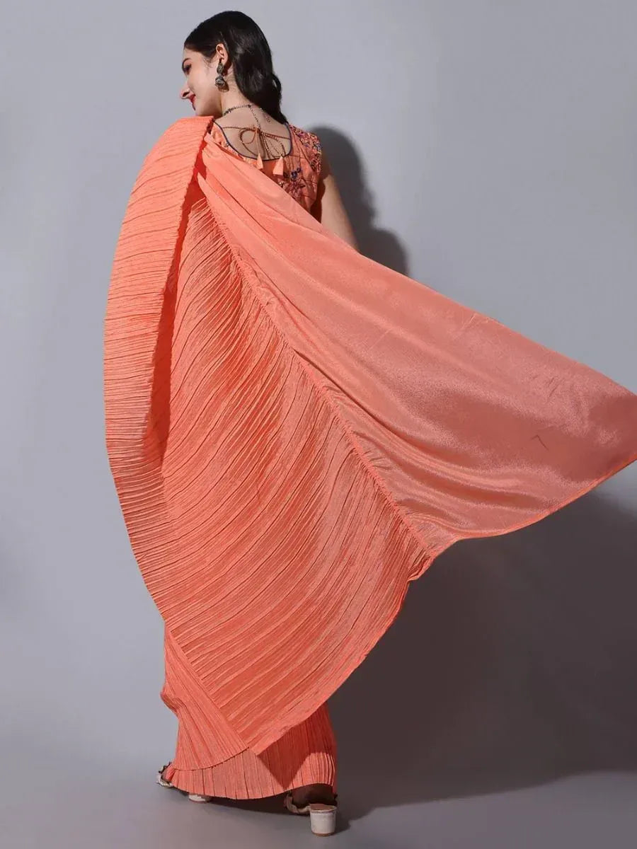 Woman in flowing peach pleated saree with embroidered blouse, ethnic Indian wear