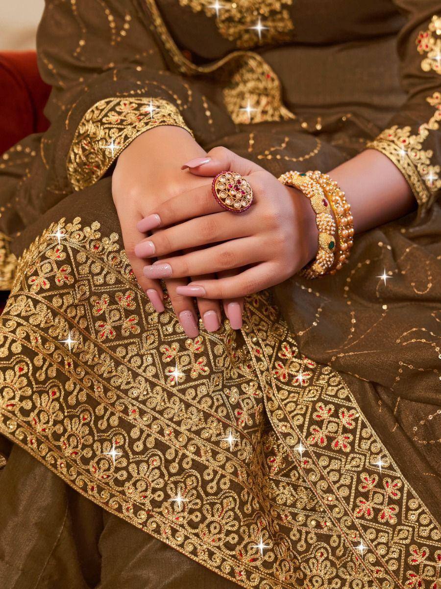 Elegant brown ethnic wear with gold embroidery, statement ring, and bangles for festive occasions.
