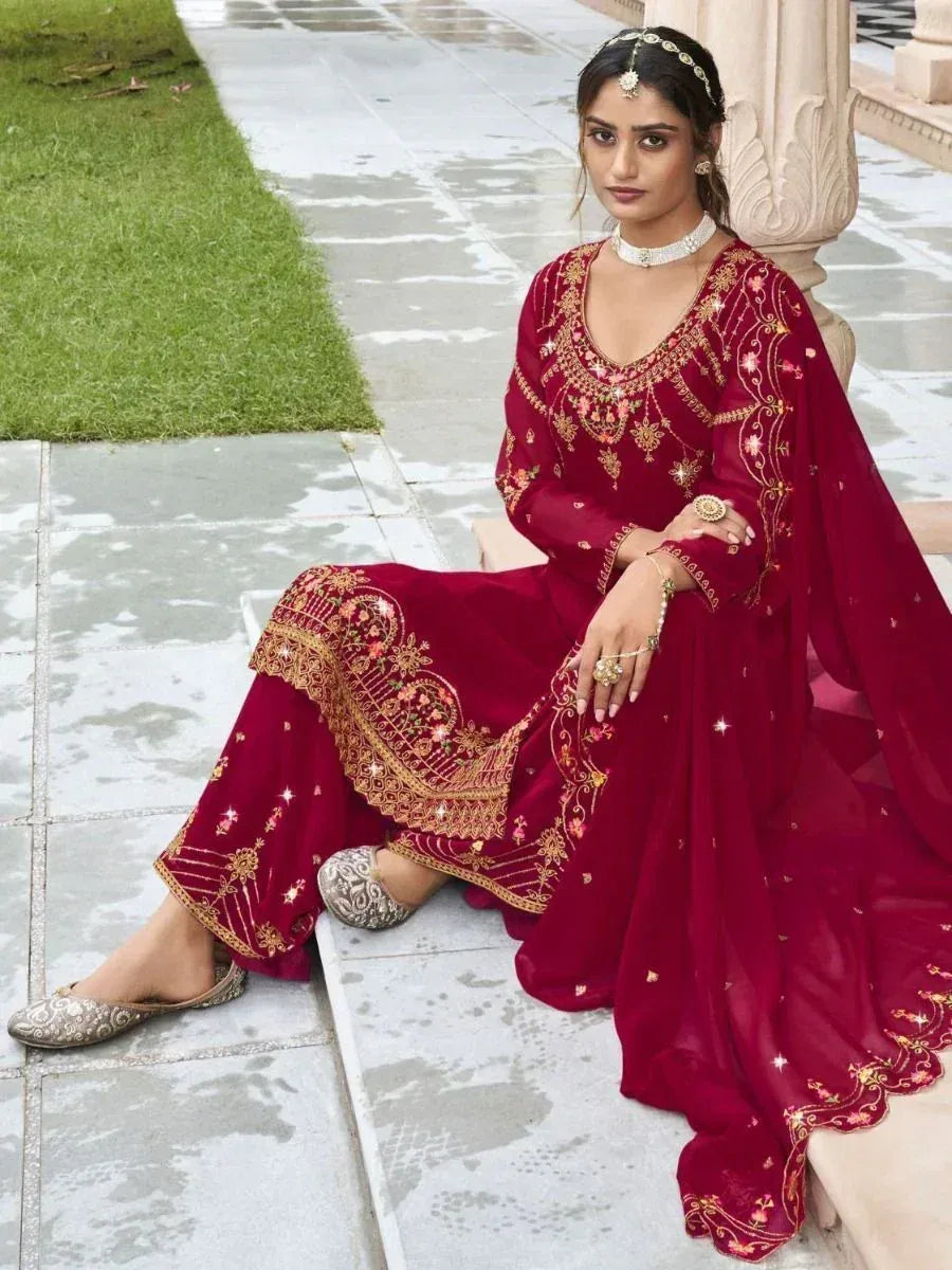 Woman in a maroon embroidered salwar kameez with gold detailing, sitting outdoors