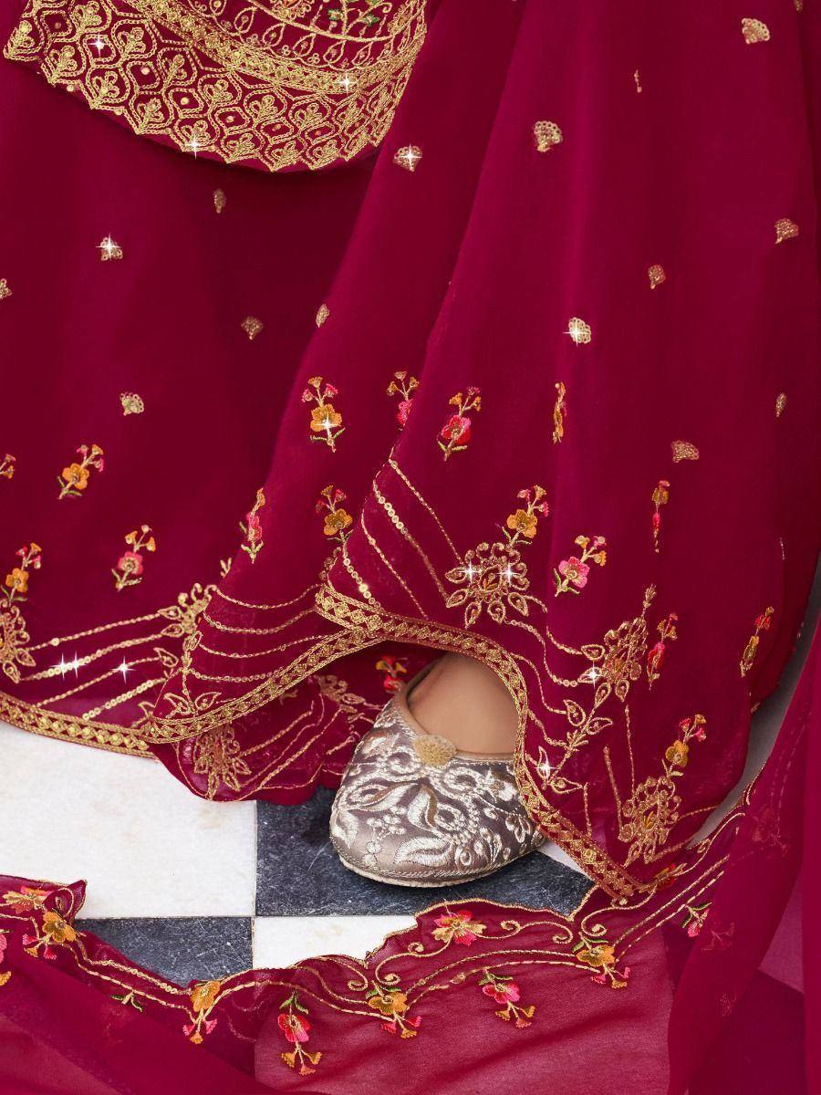Close-up of maroon lehenga with gold embroidery and traditional jutti on checkered floor