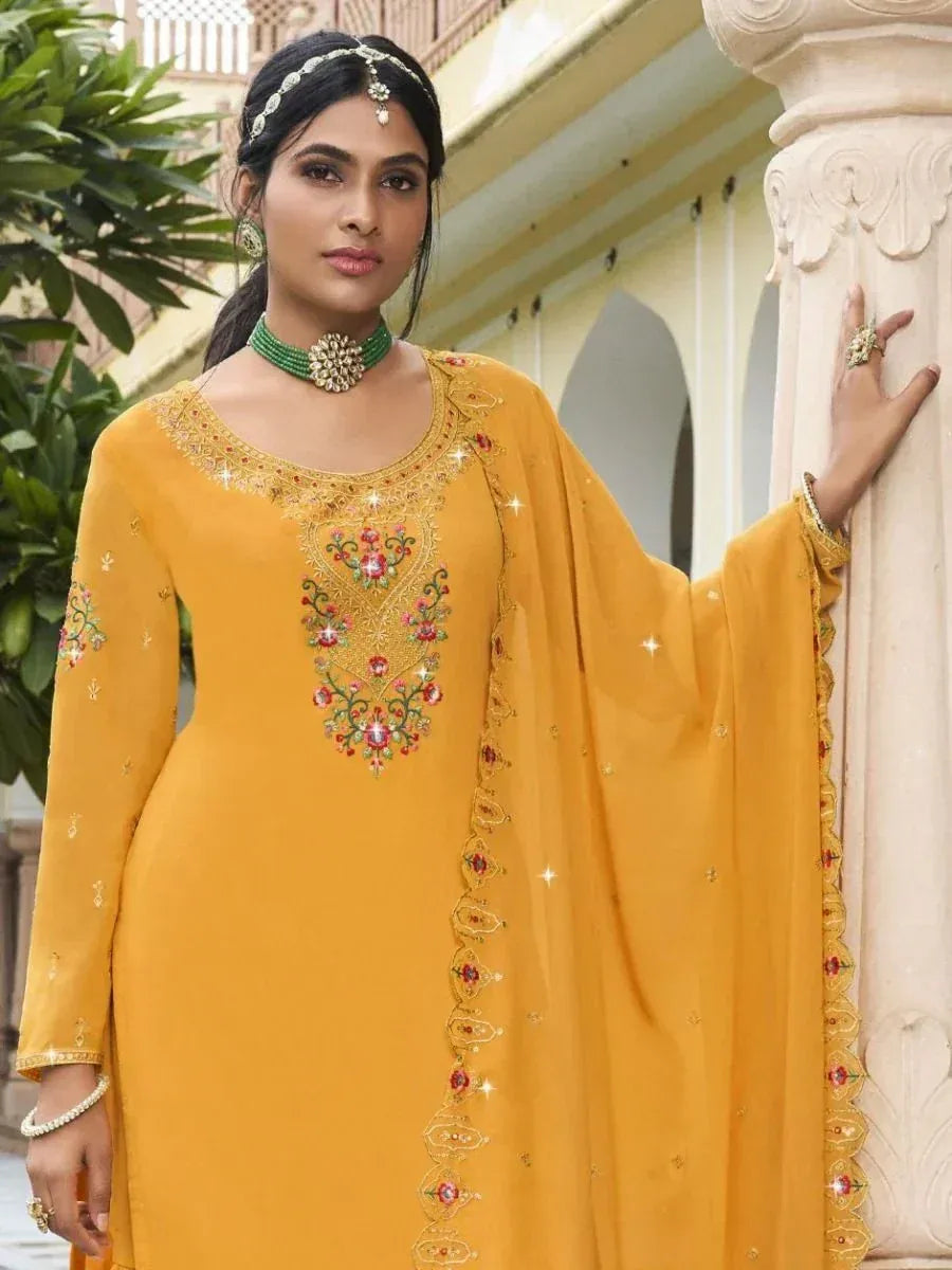 Woman in mustard yellow embroidered salwar kameez with dupatta and traditional jewelry