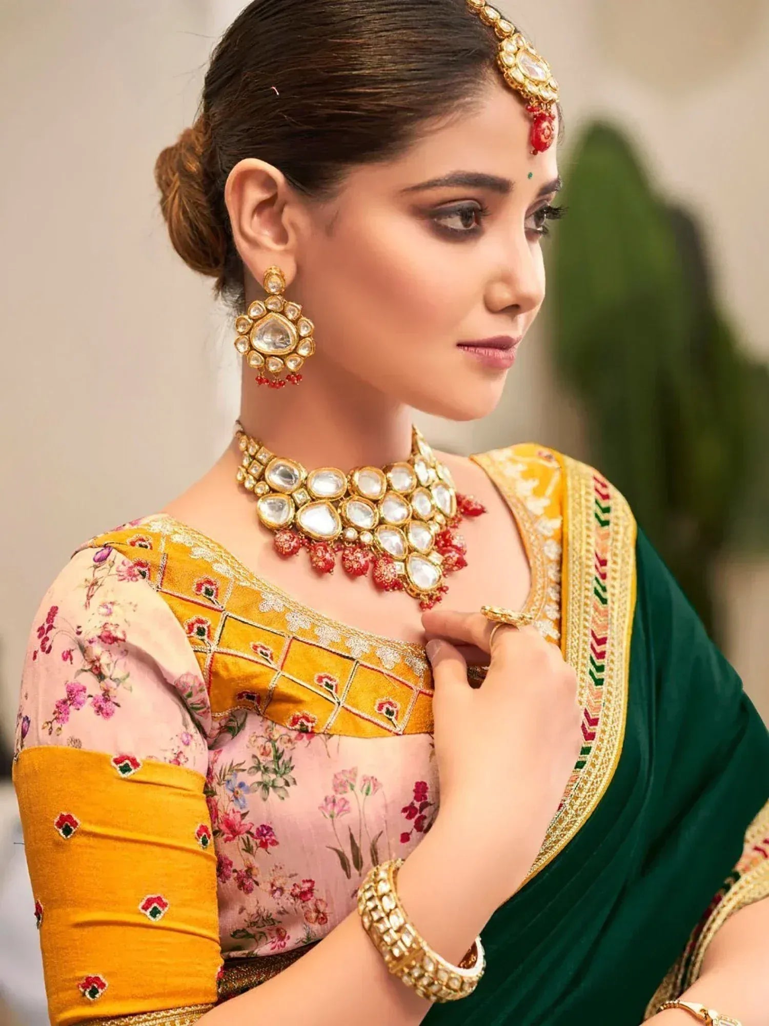 Woman in floral blouse and green saree with gold jewelry, traditional Indian ethnic wear