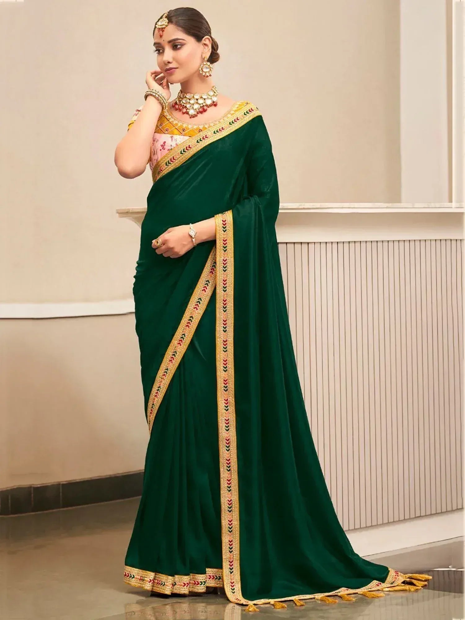 Emerald green velvet saree with gold embroidered border and pink floral blouse, styled with traditional Indian jewelry