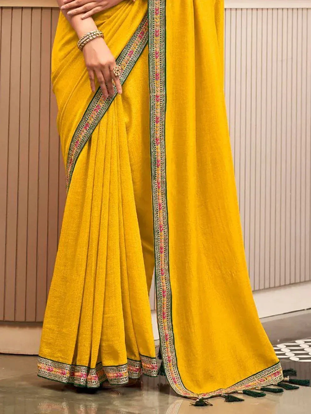 Vibrant yellow ethnic saree with embroidered border and tassels, perfect for Indian occasions