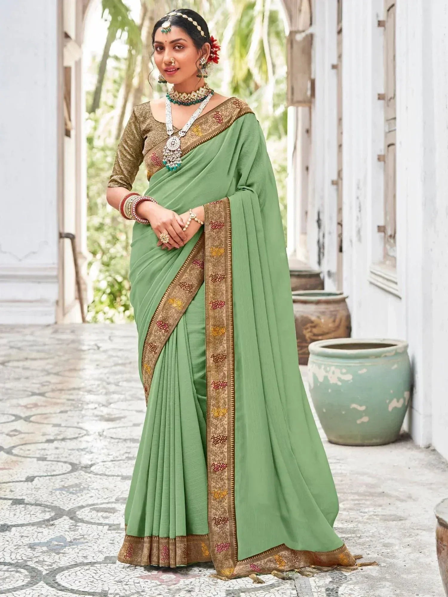Green saree with gold floral border, paired with designer blouse and traditional jewelry for ethnic wear