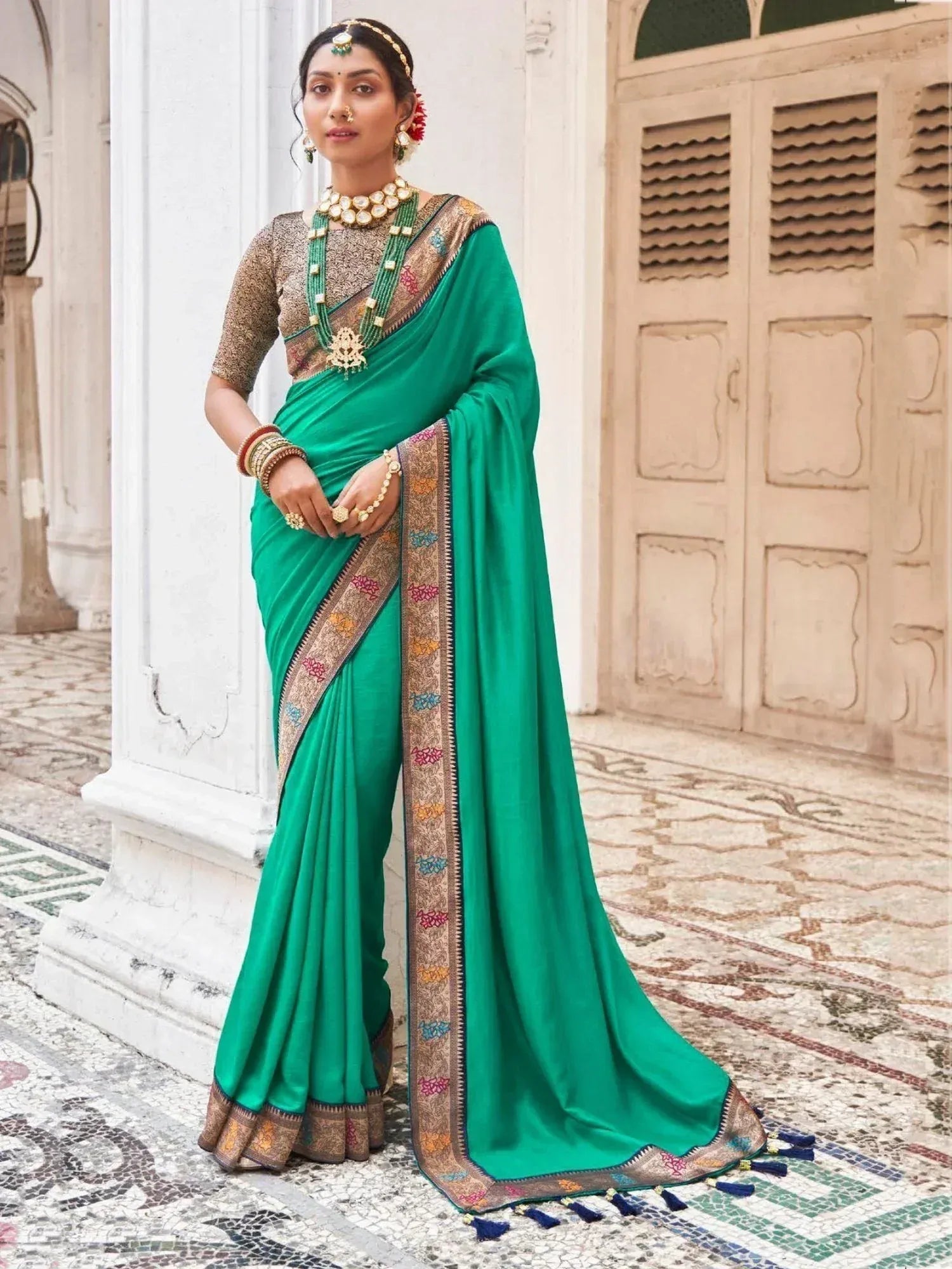 Emerald green saree with embroidered border and gold blouse, styled with traditional Indian jewelry for ethnic wear.