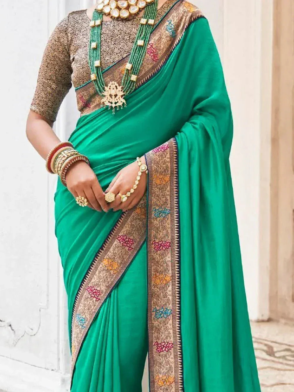Emerald green saree with embroidered border, paired with gold jewelry and printed blouse for ethnic wear